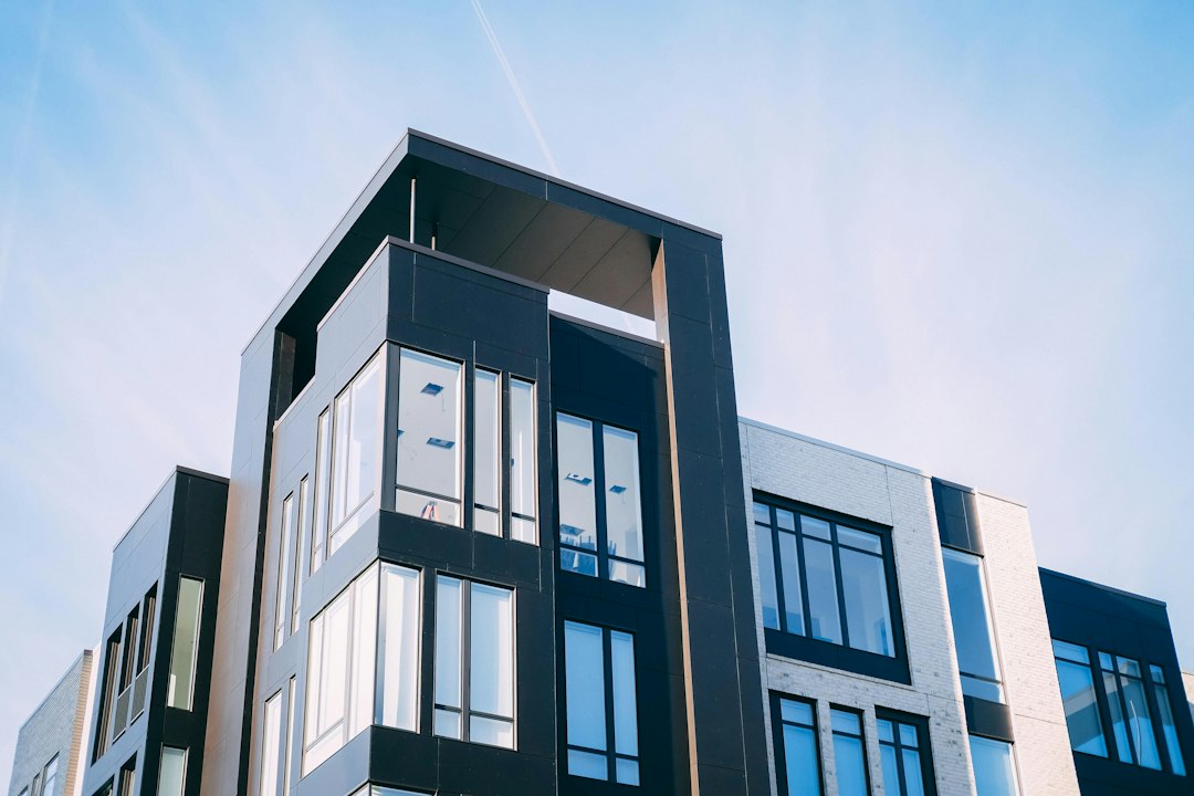 Apartment building exterior with white brick and dark cladding viewed from below